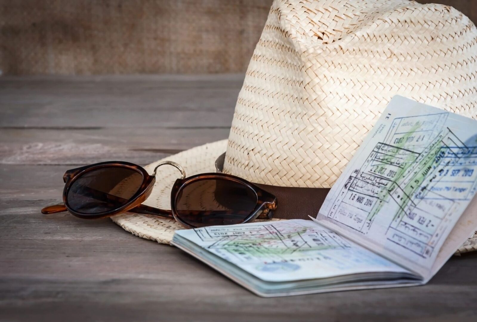 A straw hat, sunglasses and passport on the table.