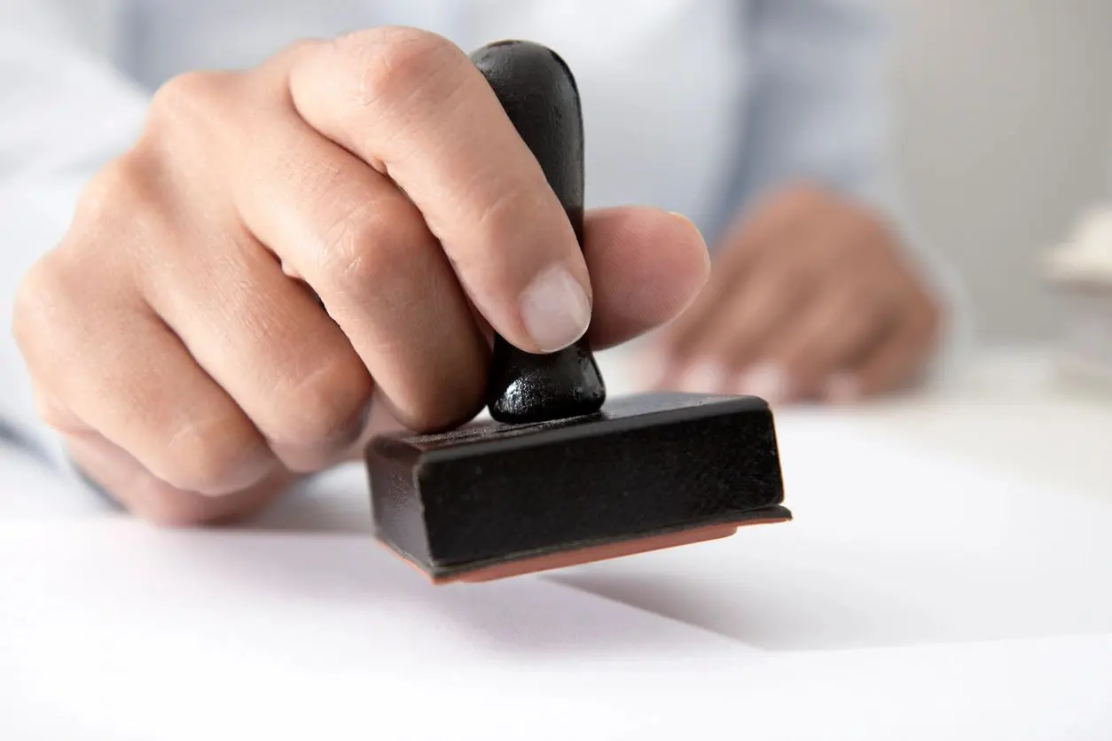 A person is holding a rubber stamp on the table