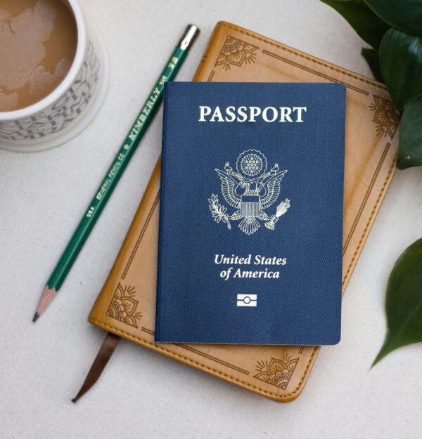 A passport sitting on top of a book next to a pencil.